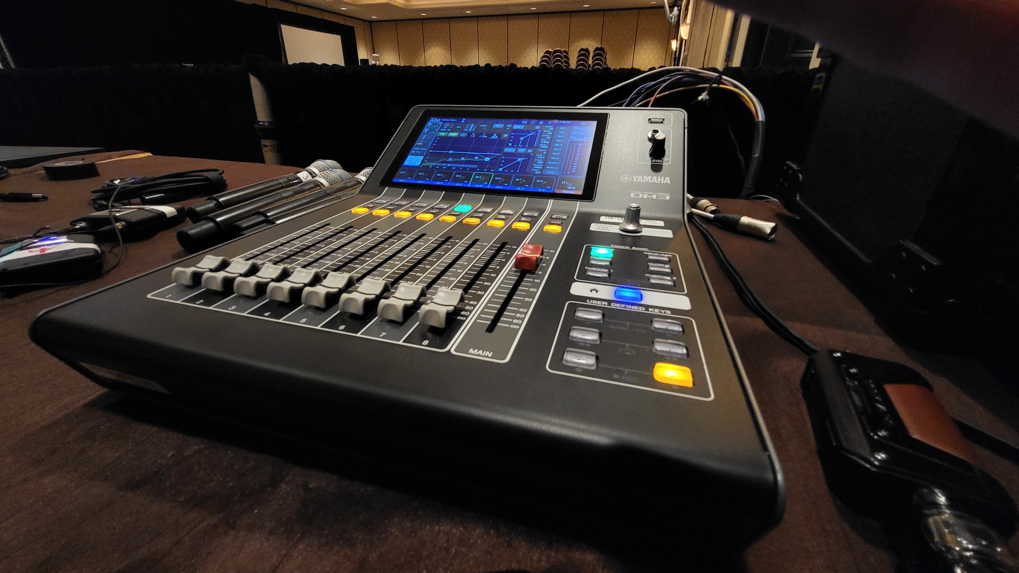 Yamaha DM3 digital audio mixing console with professional handheld microphones at a live event